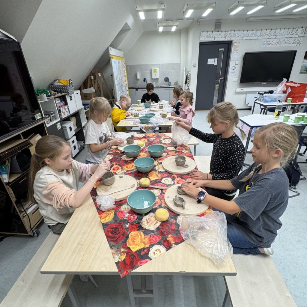 Poisid ja tüdrukud istuvad kooli keraamikaringis ümber laua ja voolivad savist asju.